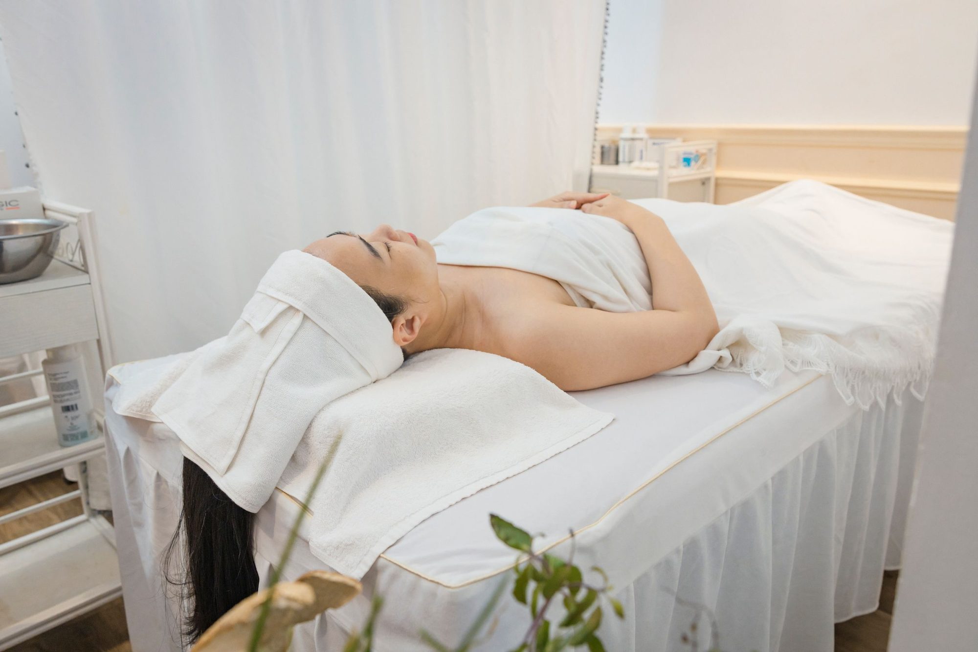 Guest resting under a white blanket in a bright treatment room