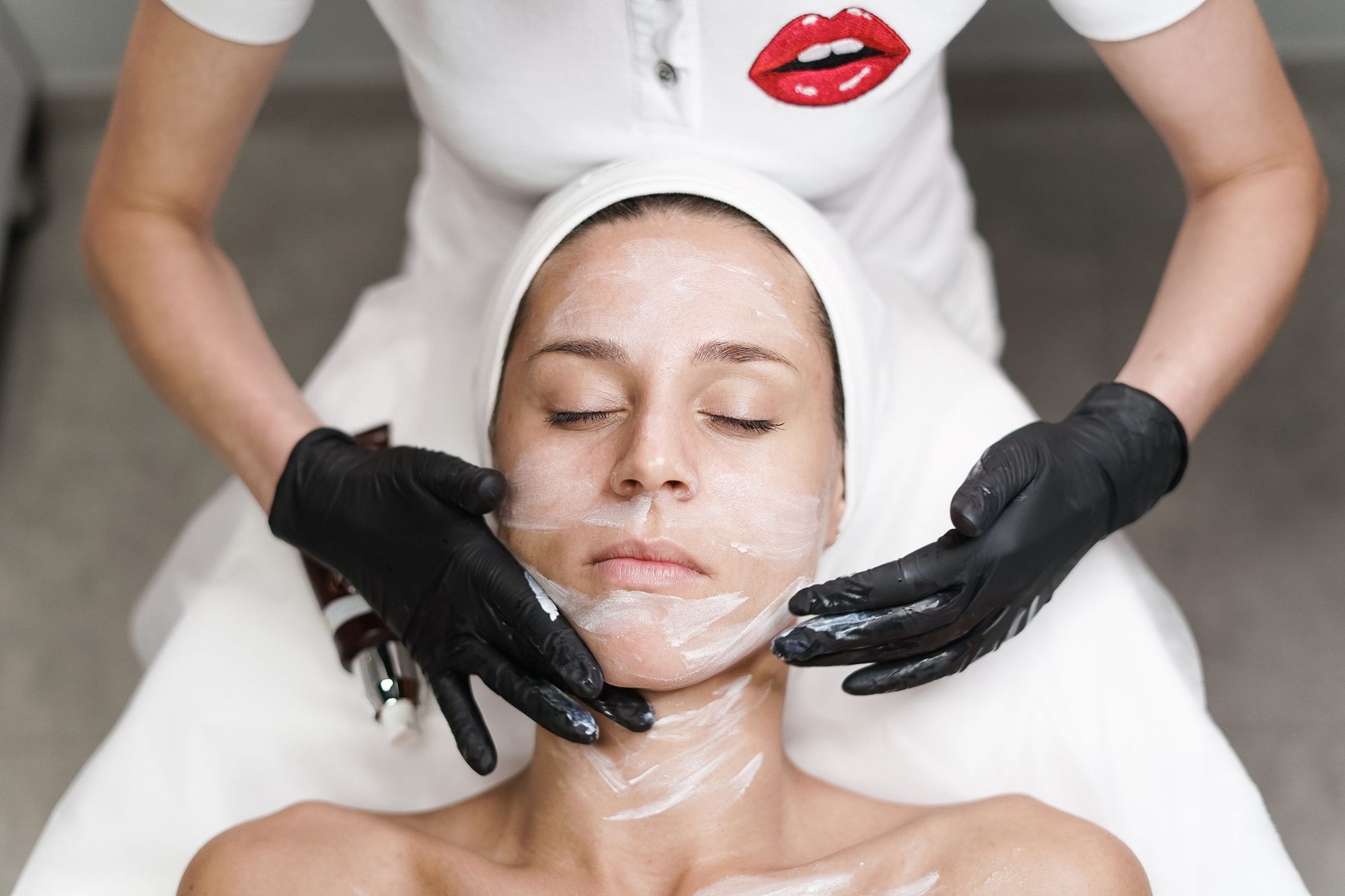 Esthetician removing a clay mask during a facial