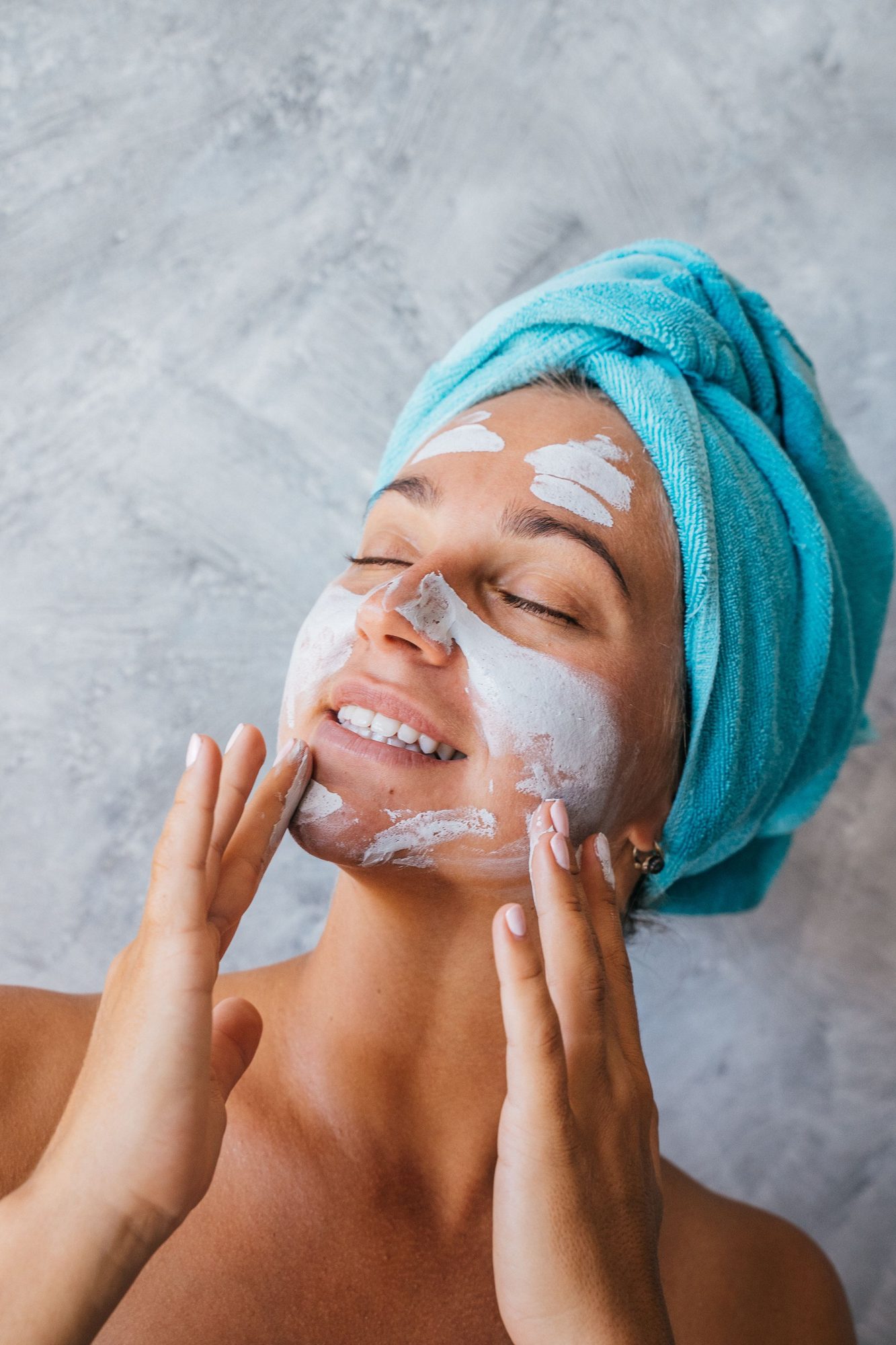 Woman with a towel wrap applying face cream